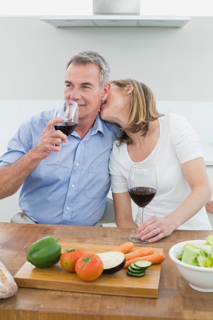 Pareja amorosa con copas de vino en la cocina