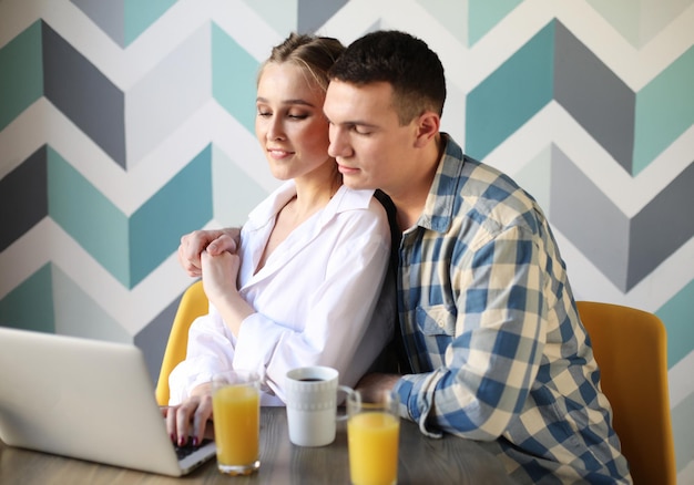 Pareja amorosa desayunando y mirando la computadora portátil