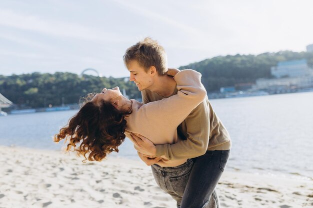 Una pareja amorosa se divierte, se ríen, se abrazan y disfrutan de una cálida tarde de verano. Pareja romántica de pie junto al mar bajo el sol y pasando tiempo juntos.