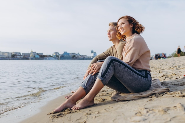 Una pareja amorosa se divierte, se ríen, se abrazan y disfrutan de una cálida tarde de verano. Pareja romántica sentada junto al mar. Retrato de un chico abrazando a su novia.