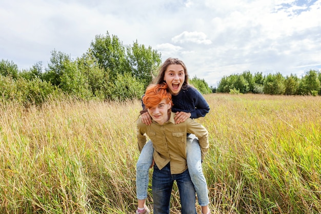 Pareja amorosa divirtiéndose en la naturaleza al aire libre Hombre joven feliz que lleva a cuestas a su novia