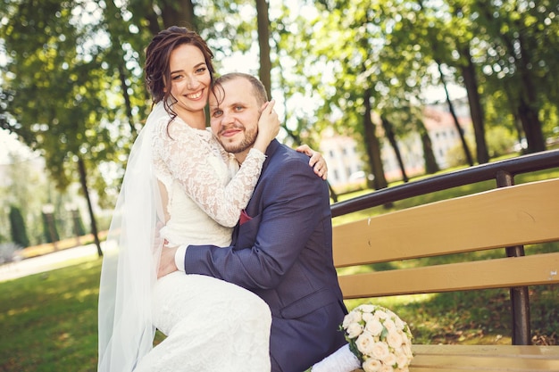 Una pareja amorosa de elegantes recién casados camina y se besa en la ciudad vieja en un día soleado de verano