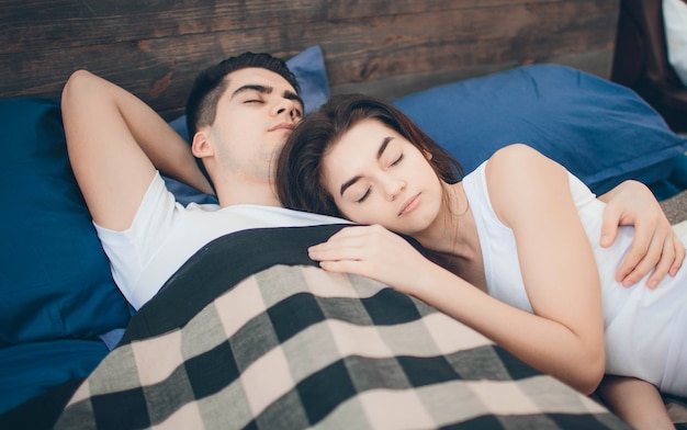 Una pareja amorosa está acostada en la cama. Dormitorio luminoso y acogedor. Amor y consuelo familiar.