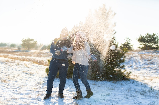 Pareja amorosa jugar bolas de nieve en invierno en el bosque. Tirarse nieve. Ríete y pasa un buen rato