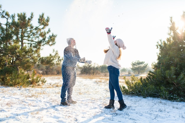 Pareja amorosa jugar bolas de nieve en invierno en el bosque. Tirarse nieve. Ríete y pasa un buen rato