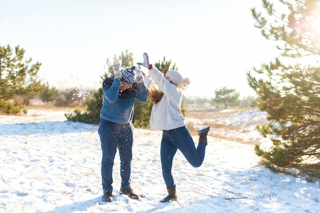 Pareja amorosa jugar bolas de nieve en invierno en el bosque