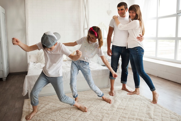 Pareja amorosa mirando el baile de sus hijos en casa.