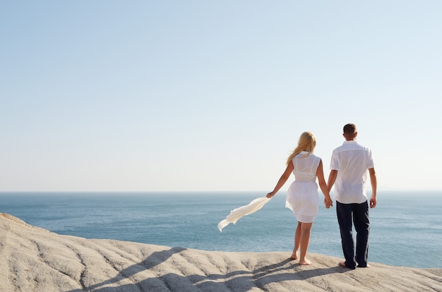 Pareja amorosa mirando el mar tomados de la mano