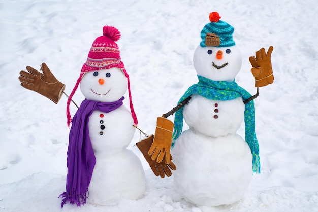 Una pareja amorosa de muñecos de nieve. Fondo de Navidad con par de muñeco de nieve. Pareja de muñeco de nieve al aire libre. Hombre de nieve lindo con sombrero y bufanda en campo nevado. Muñecos de nieve divertidos. Tarjeta de felicitación de arte festivo.