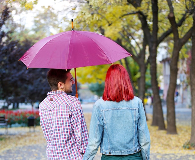 Foto pareja amorosa bajo un paraguas en el parque de otoño