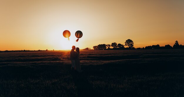 Pareja amorosa de pie en el campo con bolas de colores de helio