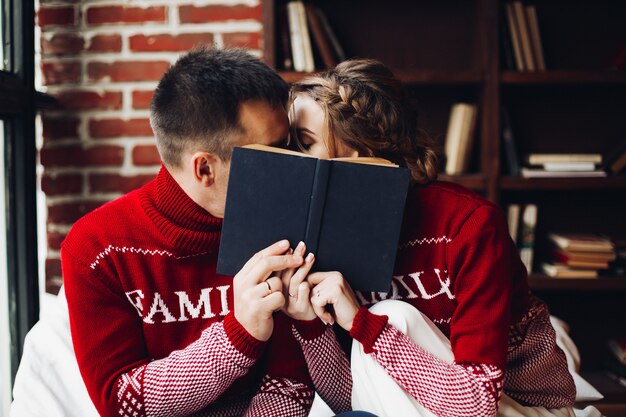 Foto pareja amorosa en puentes de invierno besándose y escondiéndose detrás del libro