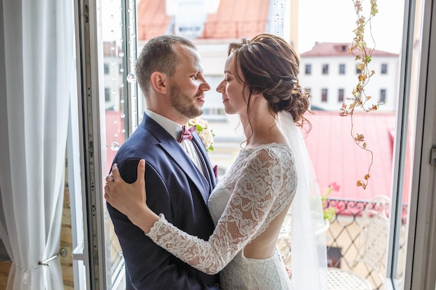 Una pareja amorosa de recién casados se para en el balcón de la ciudad vieja en un día soleado de verano