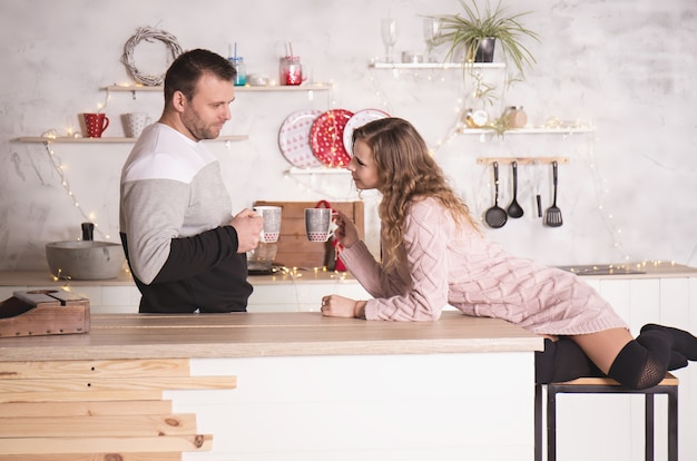 Pareja amorosa en ropa de invierno en la cocina