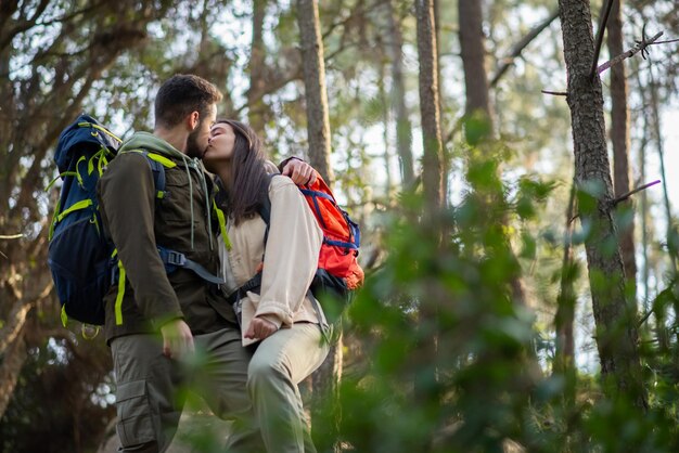 Pareja amorosa de senderismo en el bosque en otoño. Hombre y mujer parados en la colina y besándose. Amor, ocio, concepto de relación.