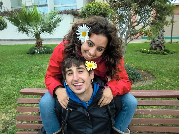 Pareja amorosa sentada en un banco del parque con flores en las orejas