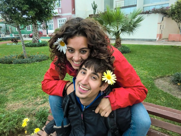 Pareja amorosa sentada en un banco del parque con flores en las orejas