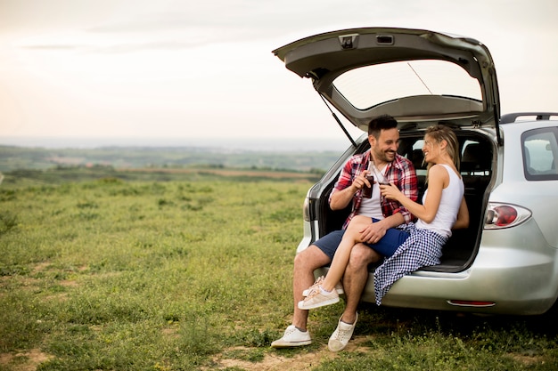 Pareja amorosa sentada en el trank coche