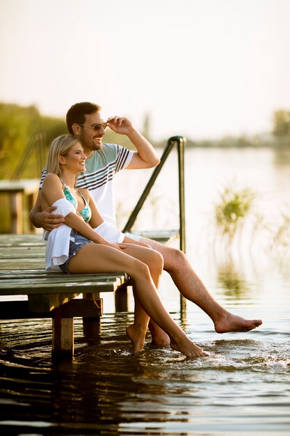 Pareja amorosa sentado en el muelle en el lago