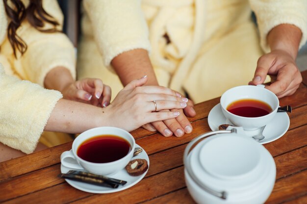 Una pareja amorosa se sienta en batas y bebe té en una mesa de madera