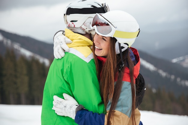 Pareja amorosa de snowboarders en las laderas del día de invierno helado abrazando