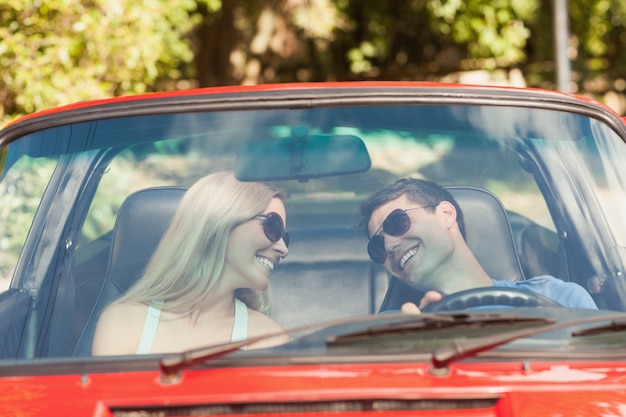 Pareja amorosa en su cabriolet rojo dando un paseo