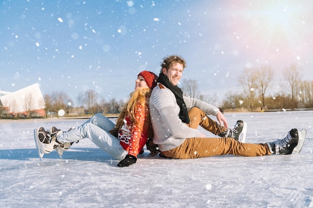 Pareja amorosa en suéteres calientes divirtiéndose en el hielo mujer y hombre patinaje sobre hielo al aire libre en el soleado nevado