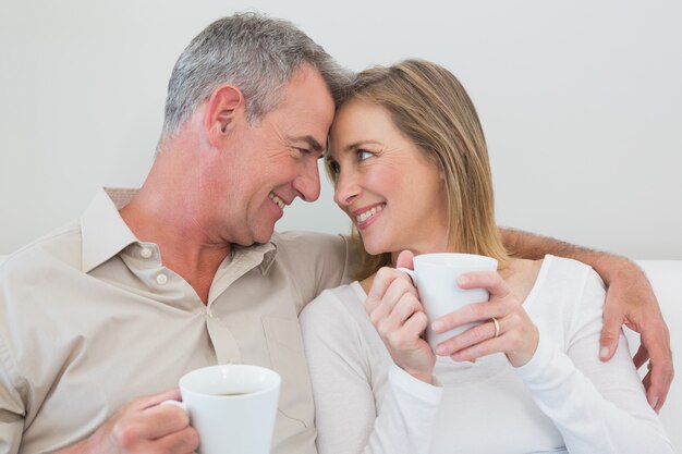 Pareja amorosa con tazas de café en la sala de estar