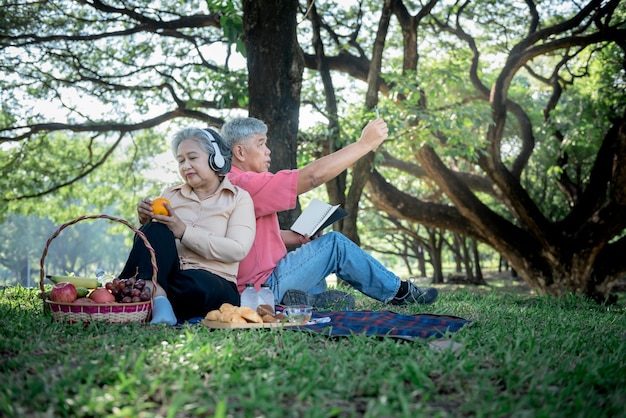 Una pareja de ancianos asiáticos atractiva esposa y esposo hacen un picnic y se relajan en el césped verde del jardín