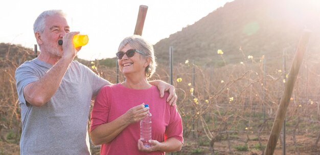 Foto una pareja de ancianos bebiendo agua mientras están de pie en la granja