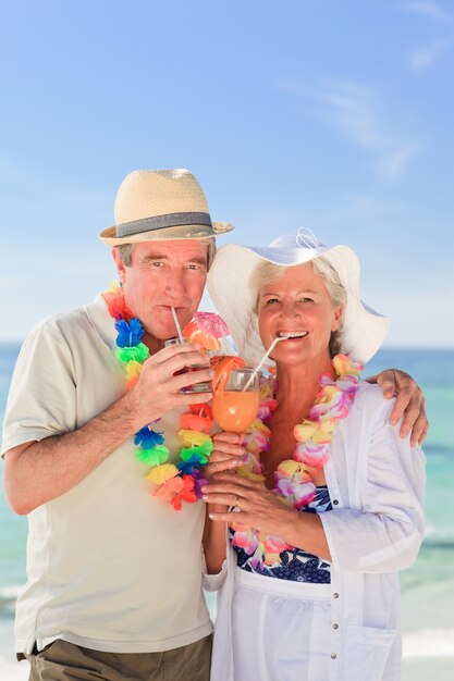 Pareja de ancianos bebiendo un cóctel en la playa