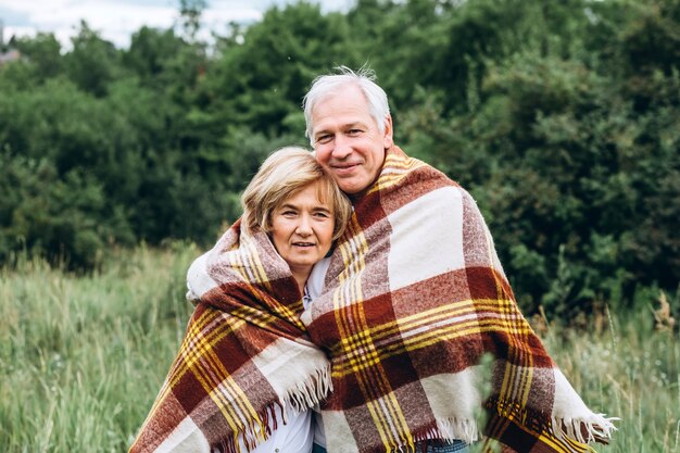 pareja de ancianos camina en la naturaleza y abrazos