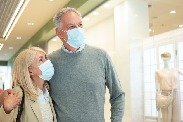 Pareja de ancianos caminando en un centro comercial durante la pandemia de coronavirus