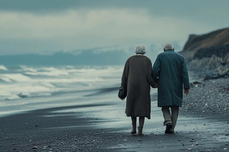 Una pareja de ancianos caminando de la mano a lo largo de una playa tormentosa al crepúsculo AI generativa