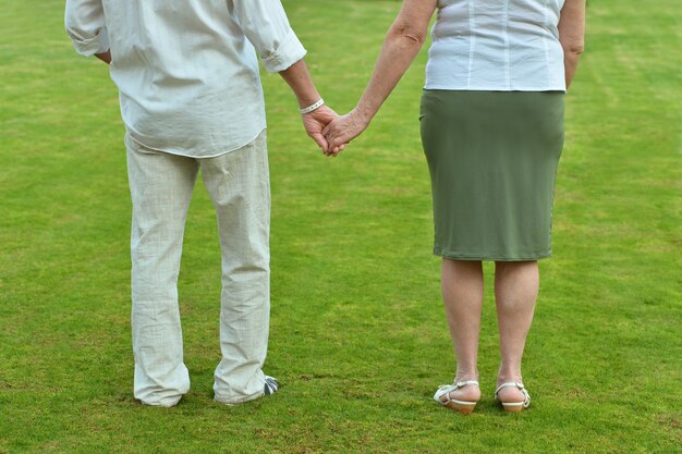 Pareja de ancianos cogidos de la mano sobre fondo de hierba verde