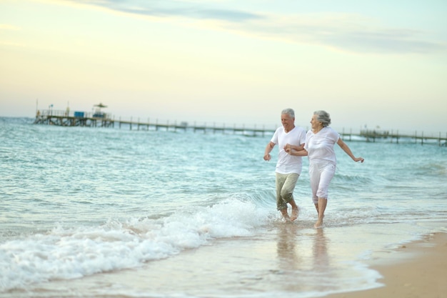 Pareja de ancianos corriendo en la playa del mar