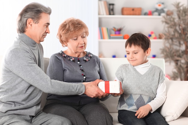 Pareja de ancianos le da un regalo a su nieto en su cumpleaños.