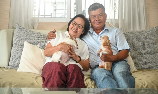 Pareja de ancianos descansando en el sofá con un chihuahua.