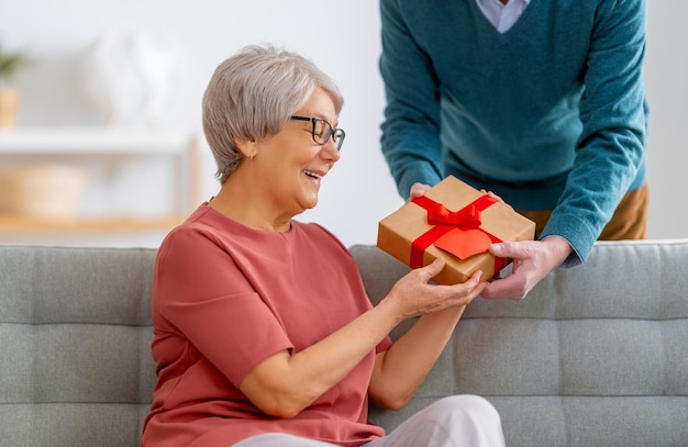 Pareja de ancianos en el día de san valentín Alegre agradable anciana sonriendo mientras recibe un regalo