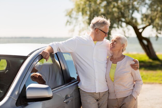 Una pareja de ancianos feliz con un coche en verano.