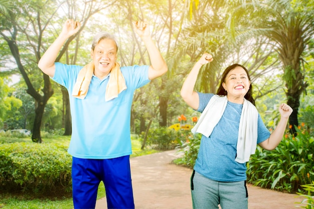 Pareja de ancianos haciendo calentamiento antes de hacer ejercicio en el parque