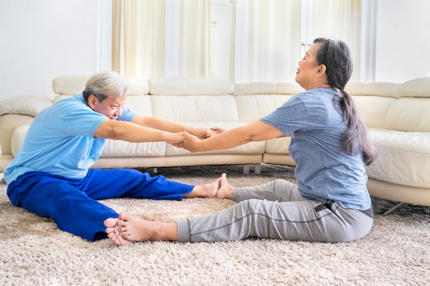 Pareja de ancianos haciendo ejercicio de calentamiento en casa