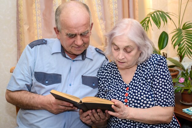 Pareja de ancianos leyendo un libro juntos en casa