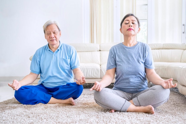 Pareja de ancianos meditando juntos en casa