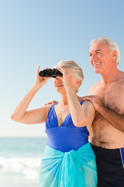 Pareja de ancianos mirando aves en la playa