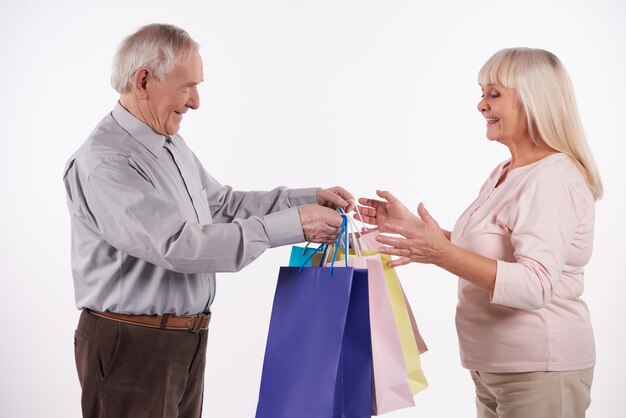 Pareja de ancianos con paquetes ir de compras en el centro comercial.