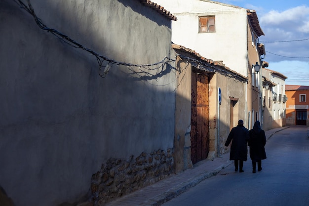 una pareja de ancianos pasea por una calle tranquila de un pequeño pueblo del interior de España.