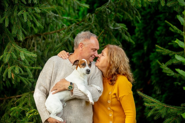 Pareja de ancianos con un perro abraza con el telón de fondo de los pinos