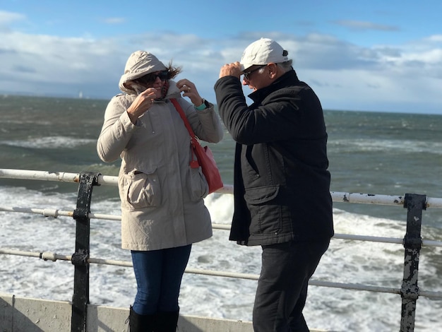 Una pareja de ancianos de pie junto al mar contra el cielo