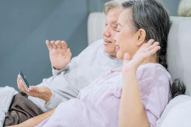 Pareja de ancianos saludando a sus nietos por celular